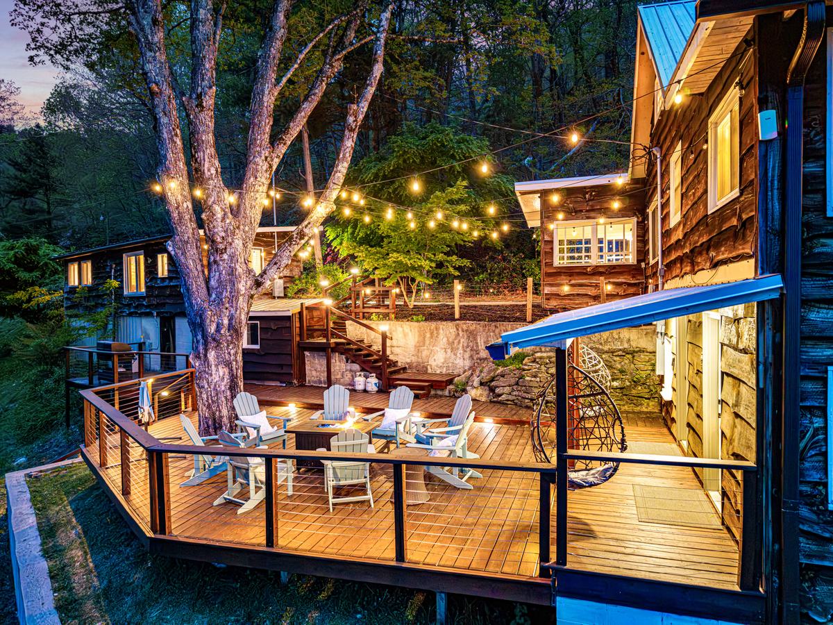 The 700 square foot deck at dusk with string lights, a fire table and a hanging egg chair