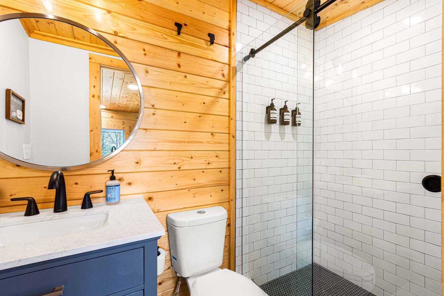 Full bathroom with a tiled walk-in shower, spruce walls and a blue vanity