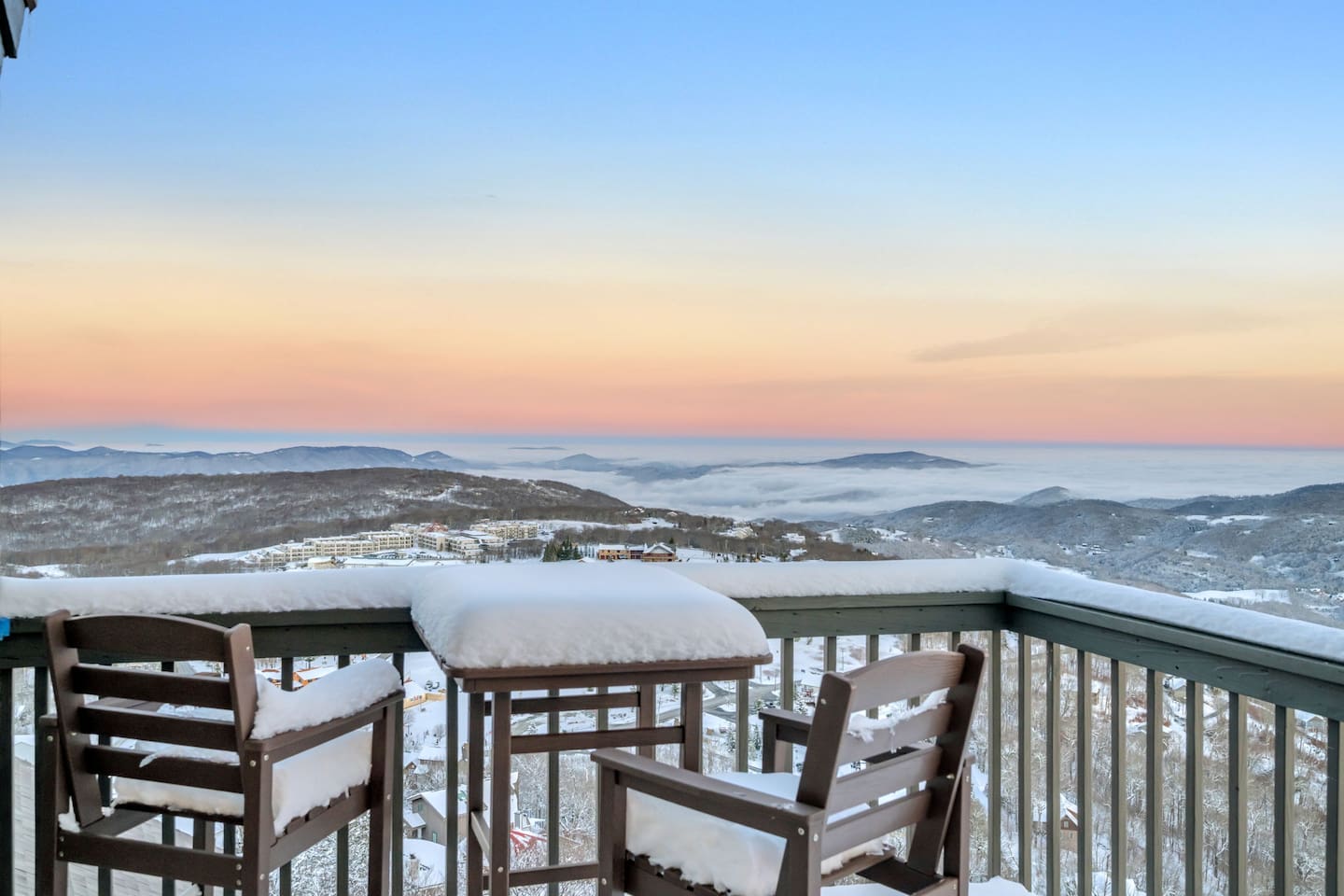 Deck chairs under snow at sunset above the clouds