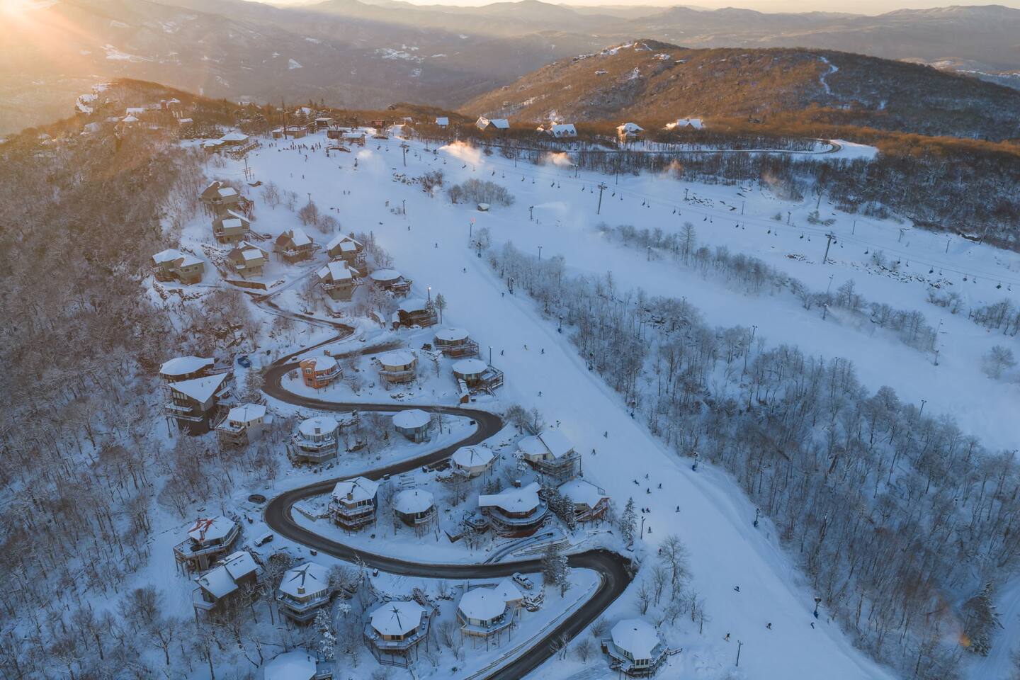 Aerial of the snow-covered Beech Mountain slopes and chalets at sunrise