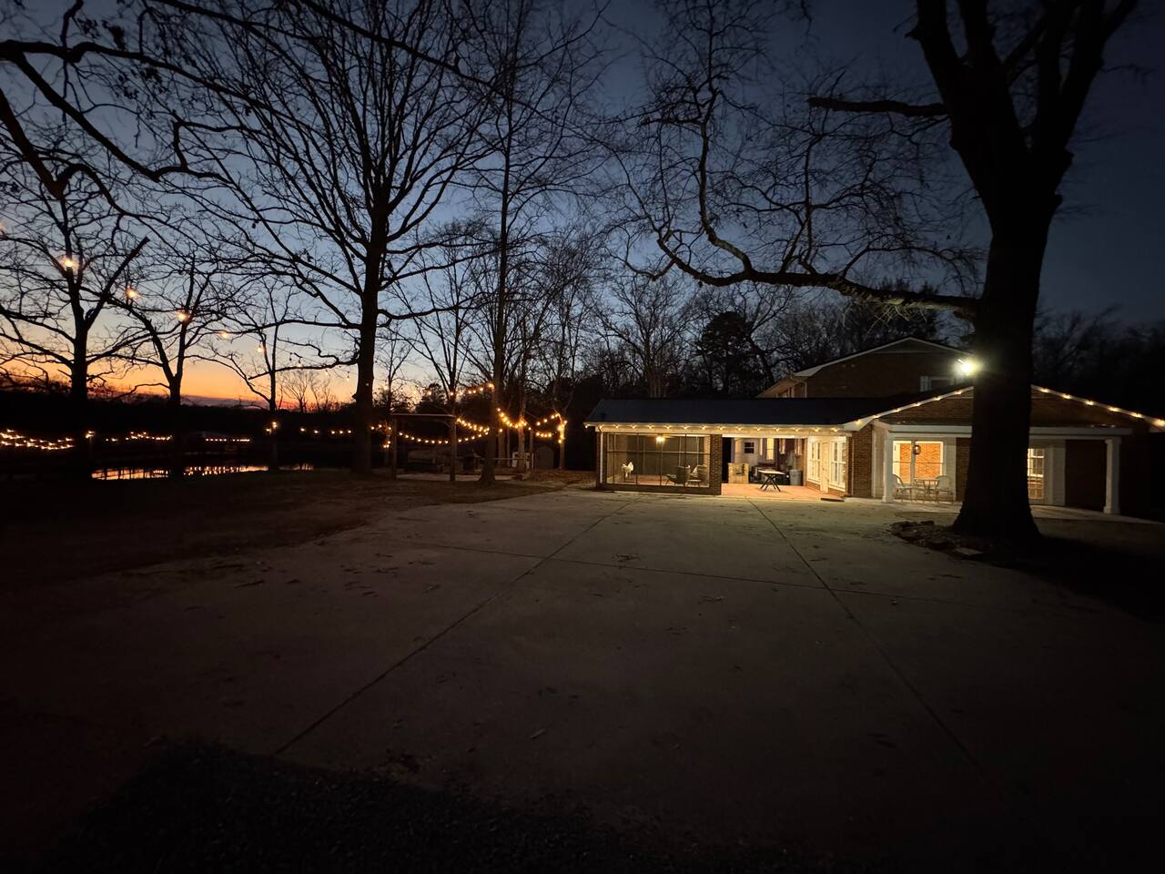 The farmhouse at Wicker Branch at dusk with string lights over the pond