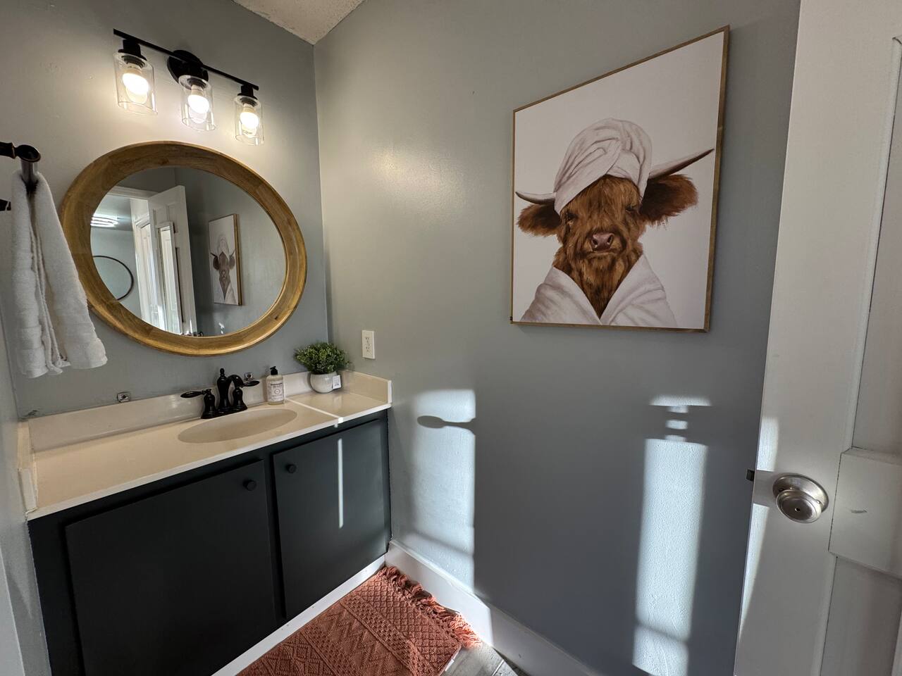 Main House bathroom vanity with a round mirror