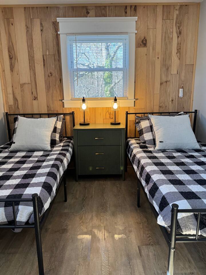 Main House kids' room with two twin beds against a wood wall